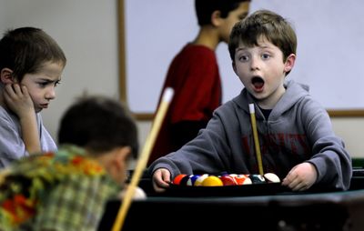 Caden Brown, right, secures the pool rack for Dylan Sande, far left, and James Star, at the Boys and Girls Club at their temporary headquarters in the Post Falls Church of the Nazarene on Tuesday.  (Kathy Plonka / The Spokesman-Review)