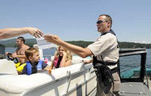 Spokane County sheriff's Deputy Jay Bailey accepts a registration form and talks to boaters about a new boater education law after a safety inspection Wednesday on Newman Lake as  Carson Kelly and Zoie Henning watch. Deputies in two boats will patrol the lake today. 
 (Jesse Tinsley / The Spokesman-Review)