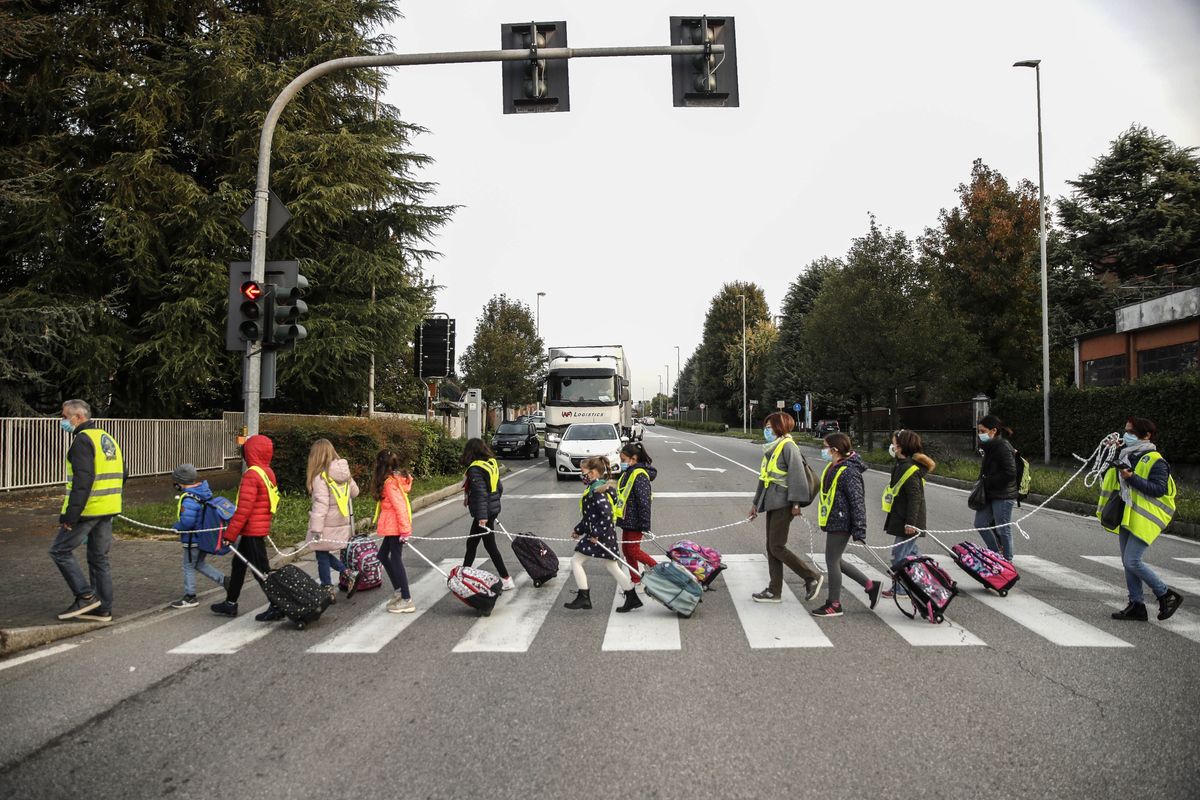 Children, escorted by volunteers, walk to school holding on to a rope to help maintain social distancing and curb the spread of COVID-19, in Bellusco, northern Italy, Tuesday, Oct. 20, 2020.  (Luca Bruno)