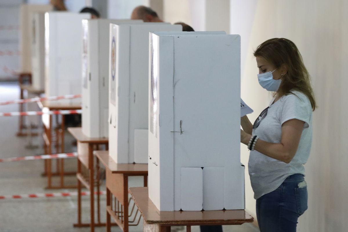 People read their ballot papers at a polling station during a parliamentary election in Yerevan, Armenia, Sunday, June 20, 2021. Armenians are voting in a national election after months of tensions over last year