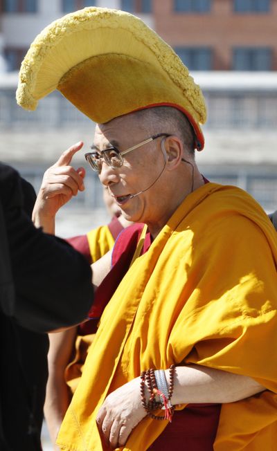 The Dalai Lama points to a ceremonial hat before a blessing at the Anacostia River on Saturday. (Associated Press)