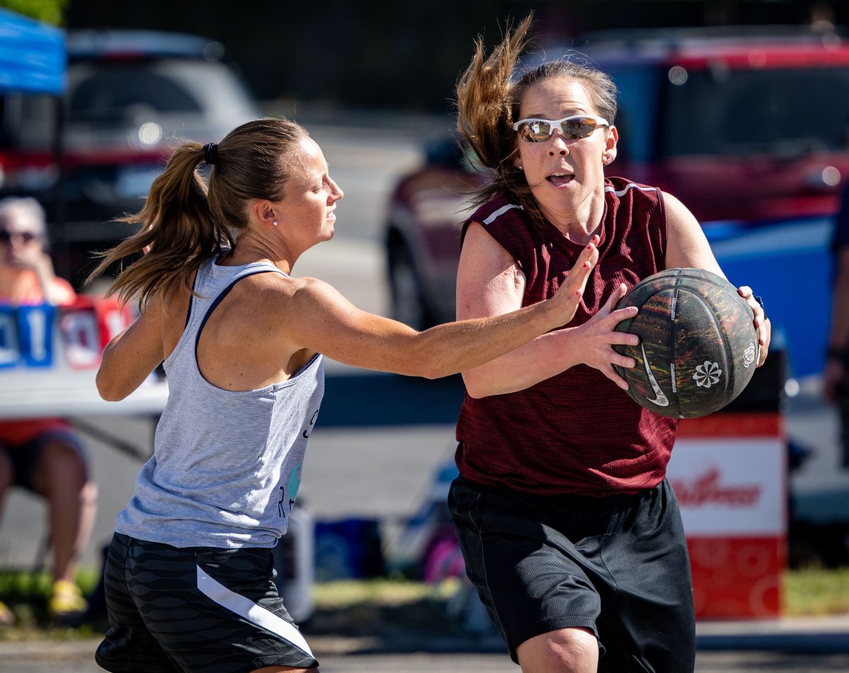 Kim Eng looks to pass as Danielle Yellam with team RHM Ballers defends during Saturday’s first-round play at Hoopfest. Eng, the last female to play in every Hoopfest, returned to the court with her co-ed team, Beating Father Time.  (COLIN MULVANY/THE SPOKESMAN)