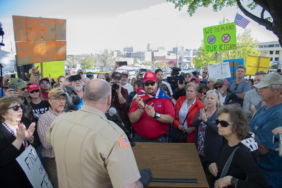 Spokane County Sheriff Ozzie Knezovich, seen from behind, faces a crowd of protesters who were marching against the statewide COVID-19 shutdown Friday, May 1, 2020 at the Spokane County Courthouse. During the tense back and forth, Knezovich made the point that no one had been ticketed or arrested in Spokane County for violating the shutdown order from the governor and didn’t think there ever would be. (Jesse Tinsley / The Spokesman-Review)