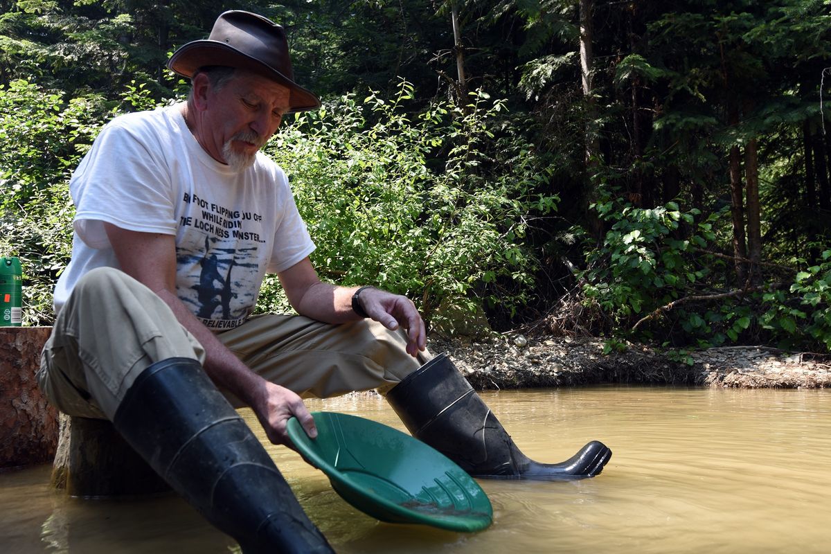 In this July 10, 2021, photo, Barry Mills from Conrad, Mont., sits in Libby Creek, panning for gold with the Northwest Montana Gold Prospectors near Libby, Mont. The Northwest Montana Gold Prospectors use their claim near Libby, Mont., to help bring the fun and excitement of panning for gold to members from across Montana and beyond. Shovels in hand, covered in dust, they work in the sandy soil above Libby Creek in the Kootenai National Forest. Like so many before them, they search the hillside and creek for the flakes of fortune that have drawn people to the remote stream since the 1860s.  (Jeremy Weber)