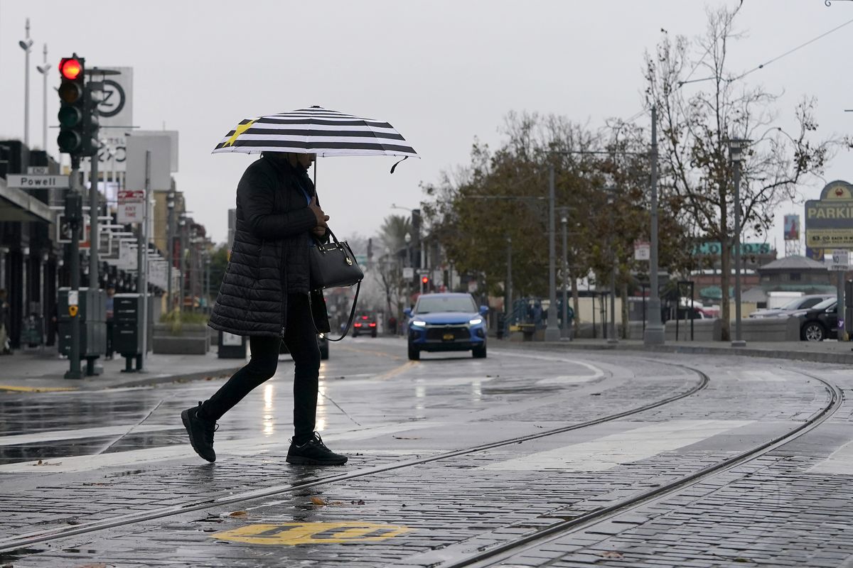 A pedestrian carries an umbrella while crossing a street at Fisherman
