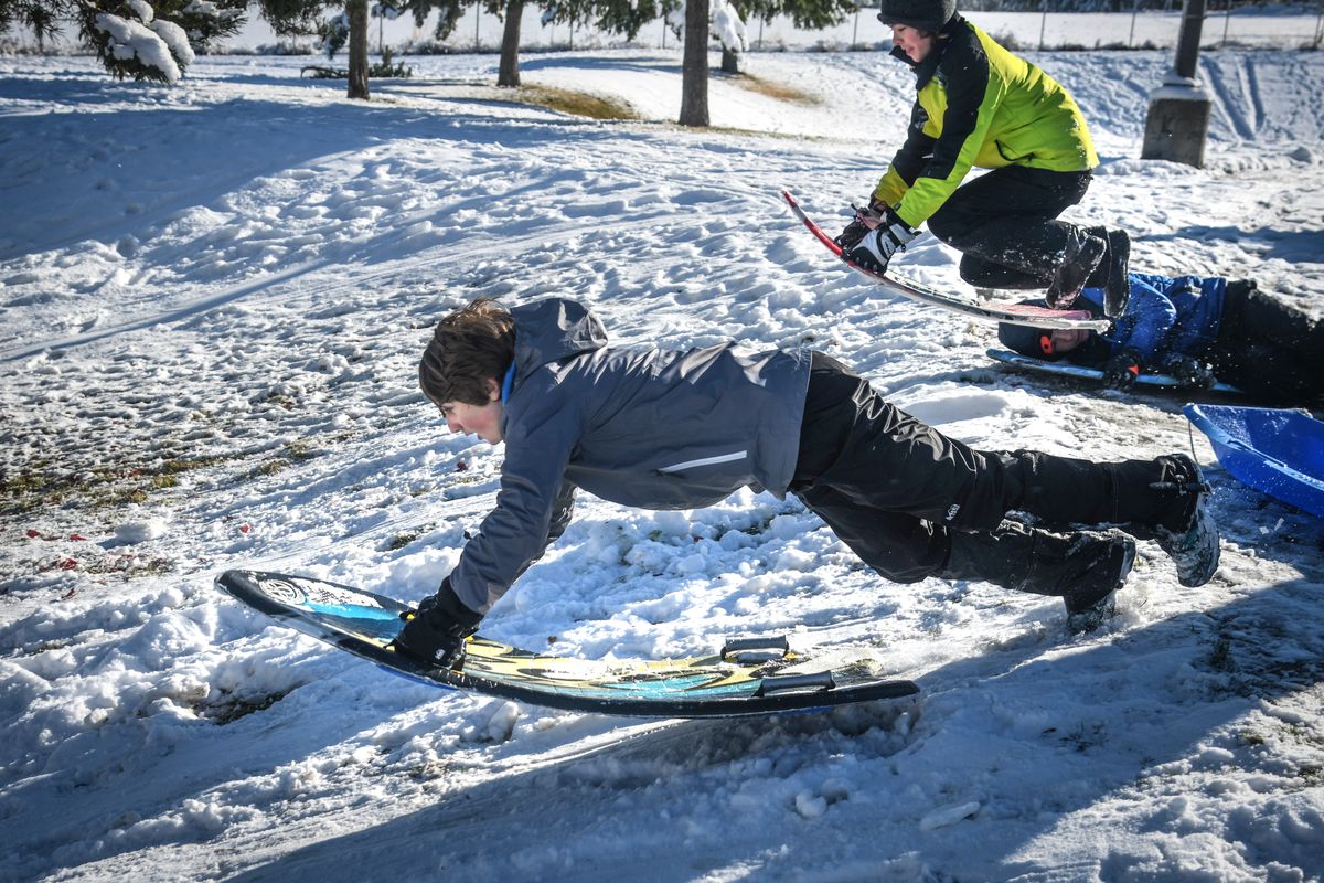 Feasting on first snow: Bodie Grangroth, 13, left, and Zander Darrington, 13, launch their sleds from the top of a hill at Chase Middle School on Oct. 24. The two were with a group from the Latter-day Saints 6th Ward that was originally planning to do a service project in the morning but canceled due to the weather.  (DAN PELLE/THE SPOKESMAN-REVIEW)