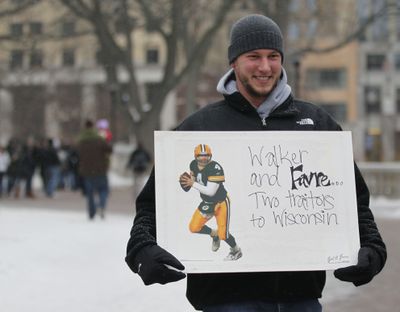 A protester holds a sign as sleet falls outside the state Capitol in Madison, Wis., on Monday. (Associated Press)