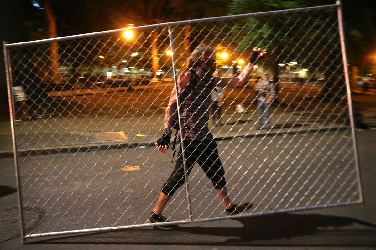 Protesters relocate a fence in front of the Justice Center, Saturday, July 18, 2020, during another night of protests in Portland, Ore.  (Mark Graves)