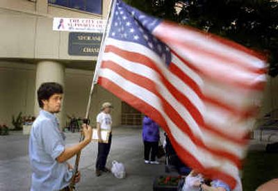 
Lyle Lebahn holds an American flag outside City Hall on Wednesday while Dave Bilsland looks to get signatures against the city camping ban ordinance. 
 (Christopher Anderson/ / The Spokesman-Review)