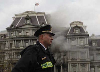 
A uniformed Secret Service officer stands on the White House grounds Wednesday as smoke pours out of the Eisenhower Executive Office Building. Associated Press photos
 (Associated Press photos / The Spokesman-Review)