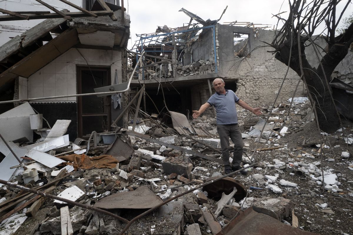 A man gestures in the yard of a house destroyed by shelling by Azerbaijan