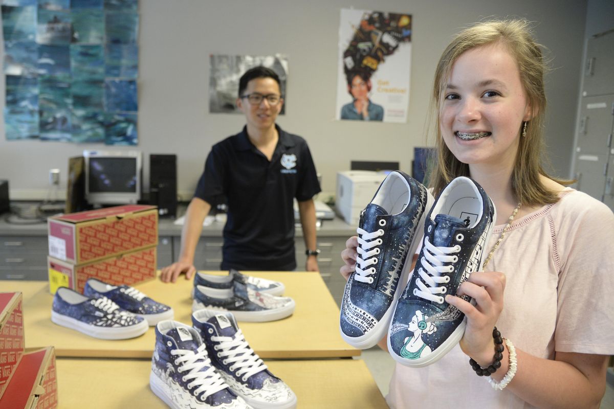 Abby Allen, a freshman at Central Valley High School, holds two Vans canvas tennis shoes she decorated with a music theme for a contest run by Vans challenging students to create their own designs on a pair of plain white shoes. Art teacher Kyle Genther looks on. (Jesse Tinsley / The Spokesman-Review)