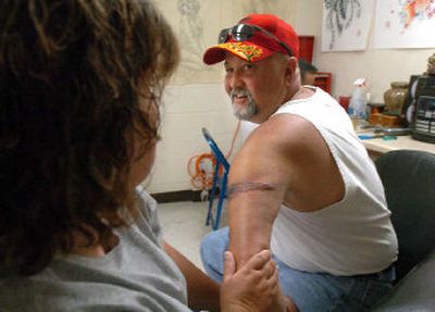 
Ken Rachels, of Post Falls, shows his wife, Carol, his first tattoo,  which he designed, at Blue Rose Tattoo in Coeur d'Alene. 
 (Jesse Tinsley / The Spokesman-Review)