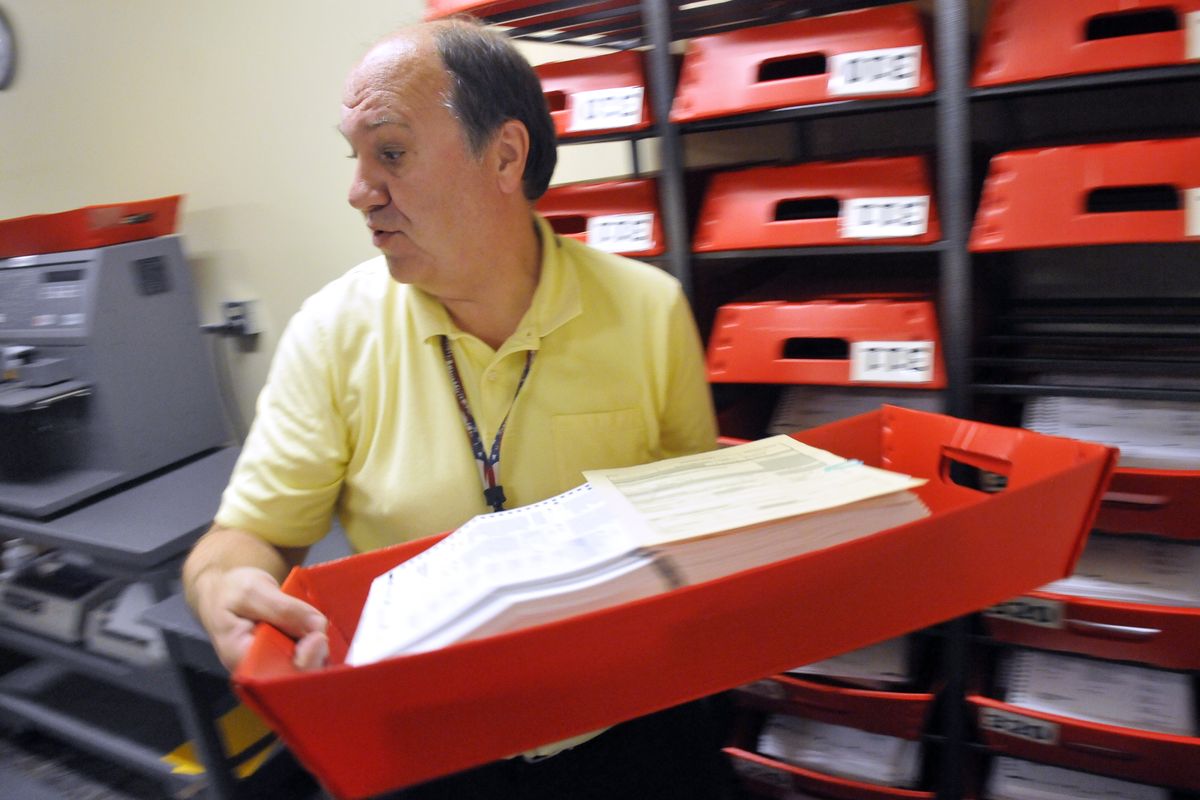 Spokane County elections worker Ralph Gruss grabs another tray of ballots to be put through counting machines at the elections office on Monday. (Jesse Tinsley)