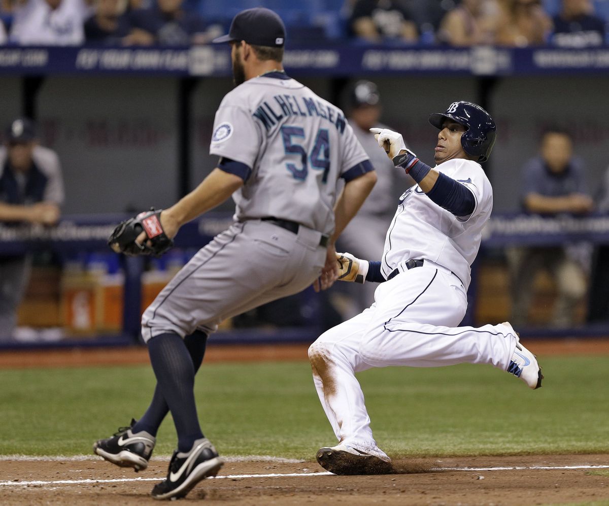 Tampa Bay’s Yunel Escobar, right, scores on a wild pitch by Seattle reliever Tom Wilhelmsen during the seventh inning Friday. (Associated Press)