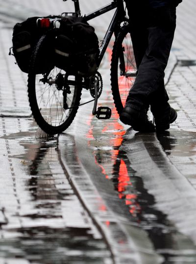 Downtown passage: A cyclist walks his bike through rain puddles along Wall Street in downtown Spokane on Monday. Today is likely to be wet, starting with light snow in the morning in many areas of the Inland Northwest, according to the National Weather Service. (Jesse Tinsley)