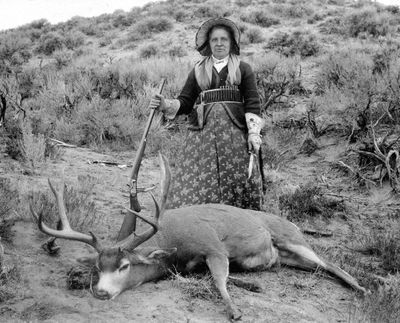 A.G. Wallihan, photographer. Augusta Wallihan—Grocery Shopping. Albumen print, circa 1895. Standing over one of her many trophy mule deer, subsistence-and-sport huntress “Gusty” Wallihan appears every inch the frontier matron with her dressy bonnet, prairie-pattern cartridge belt, floral-embroidered gauntlets, hunting knife, and Remington-Hepburn rifle.
(Museum of Northwest Colorado)