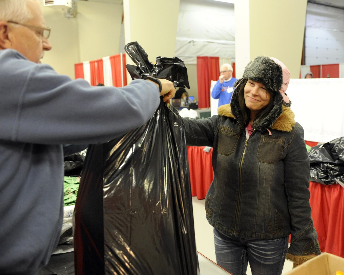 A young mother of four, who only gave her name as Korey, accepts toys for her three youngest children from volunteer bagger Bob Thompson, Thursday, Dec. 8, 2016 at the Spokane County Fair and Expo Center on the opening day of the Christmas Bureau. Korey and her friends were the first in line at the Christmas Bureau on its opening day. (Jesse Tinsley / The Spokesman-Review)