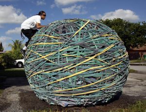ORG XMIT: FLAD102 Joel Waul, 28, climbs on top of his rubber band ball on the driveway of his home in Lauderhill, Fla., Friday, Oct. 23, 2009. Waul  who works nights restocking a Gap clothing store, has spent the last six years carefully wrapping and linking and stretching rubber bands of various sizes into the ball shape. The Guinness Book of World Records declared it the world's largest rubber band ball in 2008. (AP Photo/Alan Diaz) (Alan Diaz / The Spokesman-Review)