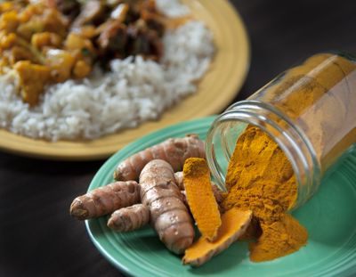 Fresh turmeric root offers bright, bold flavors when added to savory dishes, fruit smoothies and other recipes. Shown in the background are two dishes from Taste of India featuring turmeric, one with okra and tomato, and the other has cauliflower and potato. (Dan Pelle)