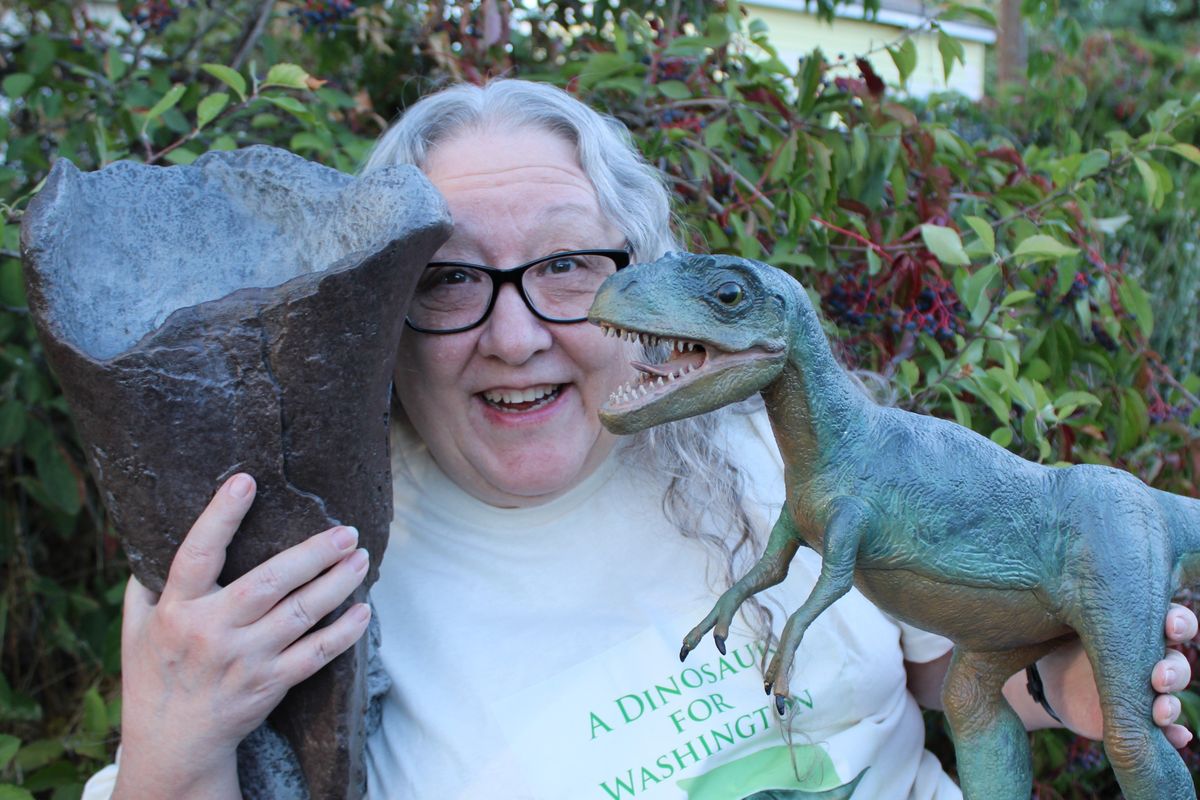 Author Kelly Milner Halls poses with a dinosaur and fossil replica. She wrote “A Dinosaur for Washington,” now on sale at Auntie’s Bookstore.  (Courtesy)