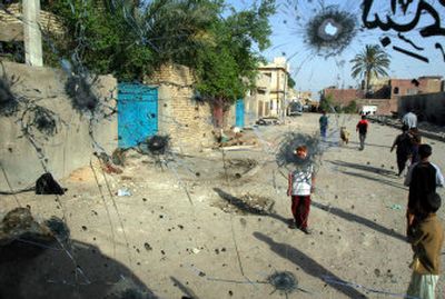 
Children walk Monday past a bullet-ridden wind-screen after a battle in Baghdad. 
 (Associated Press / The Spokesman-Review)
