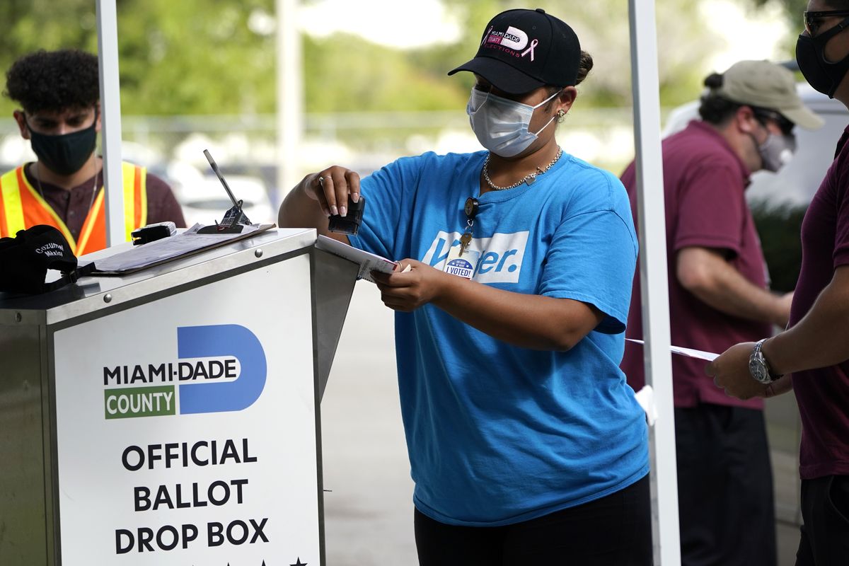 In this Monday, Oct. 26, 2020 photo, an election worker stamps a vote-by-mail ballot dropped off by a voter before placing it in an official ballot drop box before at the Miami-Dade County Board of Elections in Doral, Fla. Ballot drop boxes were enormously popular during the 2020 election, with few problems reported. Yet they have drawn the attention of Republican lawmakers in key states who say security concerns warrant new restrictions.  (Lynne Sladky)