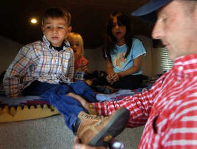 
Andy Fisk helps his son Carson Fisk, 4, with his boots  Friday at the show.
 (The Spokesman-Review)