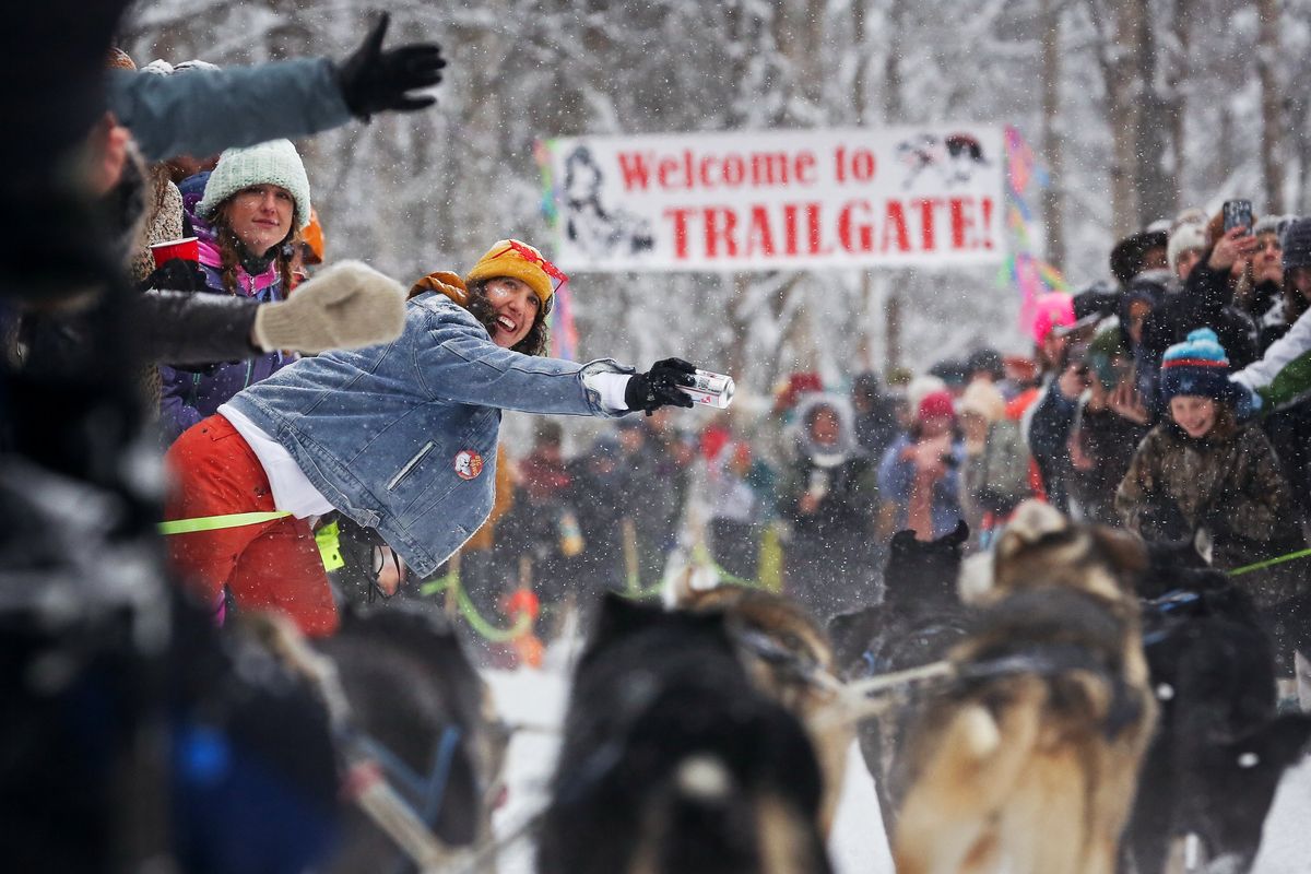 A spectator holds out a can of beer to a musher on Saturday during the 54th ceremonial start to the Iditarod Trail Sled Dog Race in Anchorage, Alaska.  (EMILY MESNER)