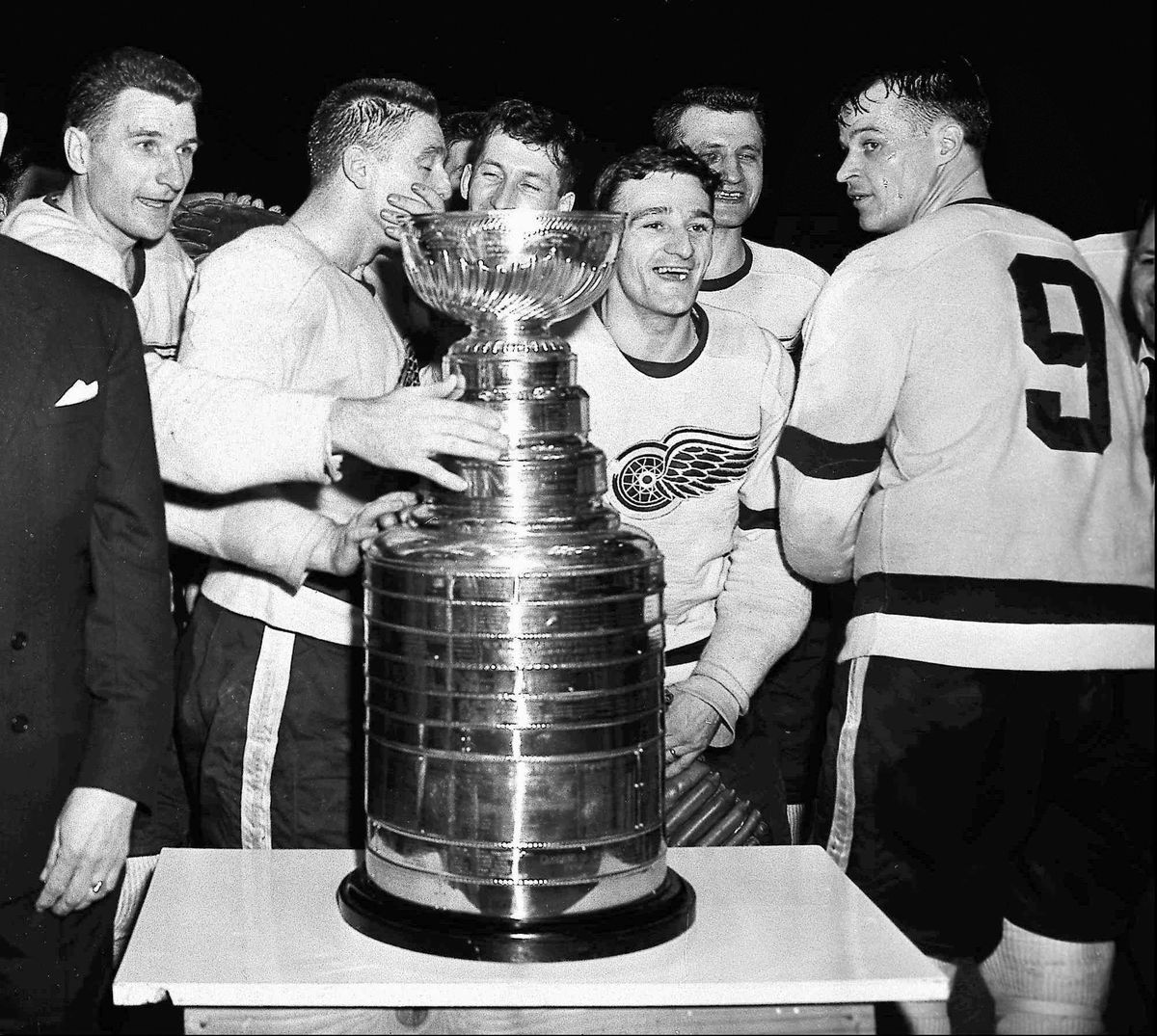In this April 14, 1955, file photo, the Detroit Red Wings, including Gordie Howe, right, surround the Stanley Cup after beating the Montreal Canadiens in the Stanley Cup Finals. The names of Howe and others on NHL championship teams from 1954-65 that are engraved on the Stanley Cup will need to be removed in 2018 to make room for the next generation of champions. (Detroit News via AP)