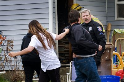Spokane police Officer Frank Erhart approaches a distraught homeowner who had just discovered his house was  extensively damaged in a fire Tuesday. Two family pets died in the blaze.  (Colin Mulvany / The Spokesman-Review)