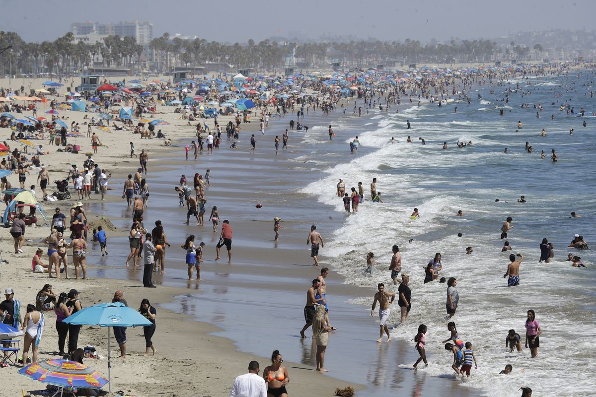 FILE – In this July 12, 2020, file photo, visitors crowd the beach in Santa Monica, Calif., amid the coronavirus pandemic. Californians headed to campgrounds, beaches and restaurants over the long holiday weekend as the state prepared to shed some of its coronavirus rules.  (Marcio Jose Sanchez)