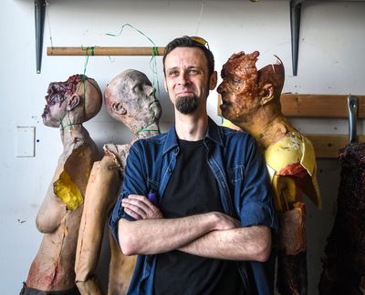 Z Nation actor Matt Davidson stands with rubber foam body of his likeness (second face from left, bottom row). The Z Nation team is liquidating a warehouse full of costumes and props used on the show. (Dan Pelle / The Spokesman-Review)
