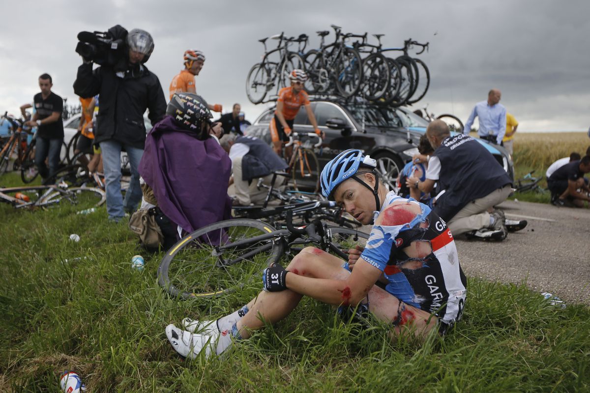 Injured American cyclist Thomas Danielson sits in the grass after a crash during Friday’s sixth stage. (Associated Press)