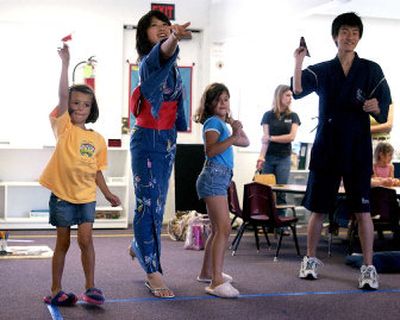 Left to right, Abby Robb, 5, Kumiko Fukamatsu, 16, Lacey Brown, 7, and Takuya Kawai, 15, fly paper airplanes they made with origami paper at Cornerstone Montessori in the Spokane Valley on Tuesday. The Japanese students are in town through the program Compass USA.
(Liz Kishimoto / The Spokesman-Review)