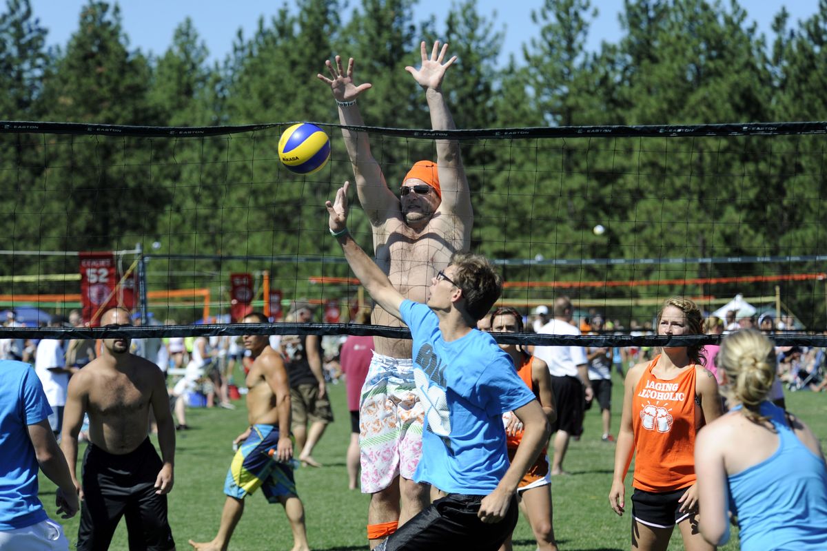 Dustin Peterson tries to block a tip by Garrett Kuntz, center, during a volleyball match Saturday at Dwight Merkel Sports Complex in northwest Spokane. Peterson plays for a team called the Raging Alcoholics, while Kuntz plays for the Dirty Six-pack. The tournament brought more than 300 teams together, mostly in casual recreational divisions, for a weekend of outdoor six-on-six volleyball. (Jesse Tinsley)