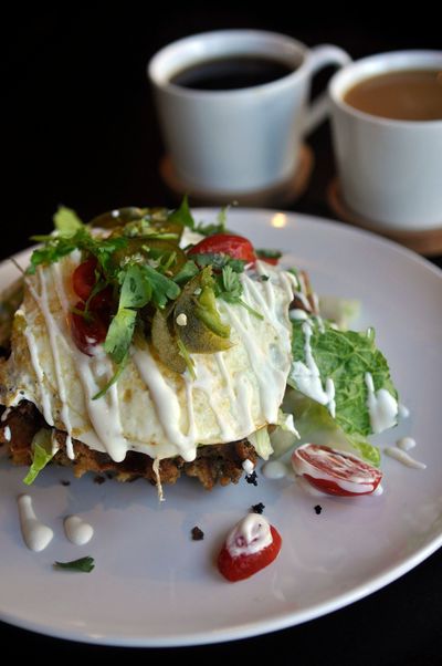 The tamale waffle, one of the signature dishes at Bruncheonette, features spicy shredded beef, two eggs, lettuce, cherry tomatoes, pickled jalapeno, crema and cilantro. Green onion and cheddar are included in the batter, along with masa.  (The Spokesman-Review photo archive)