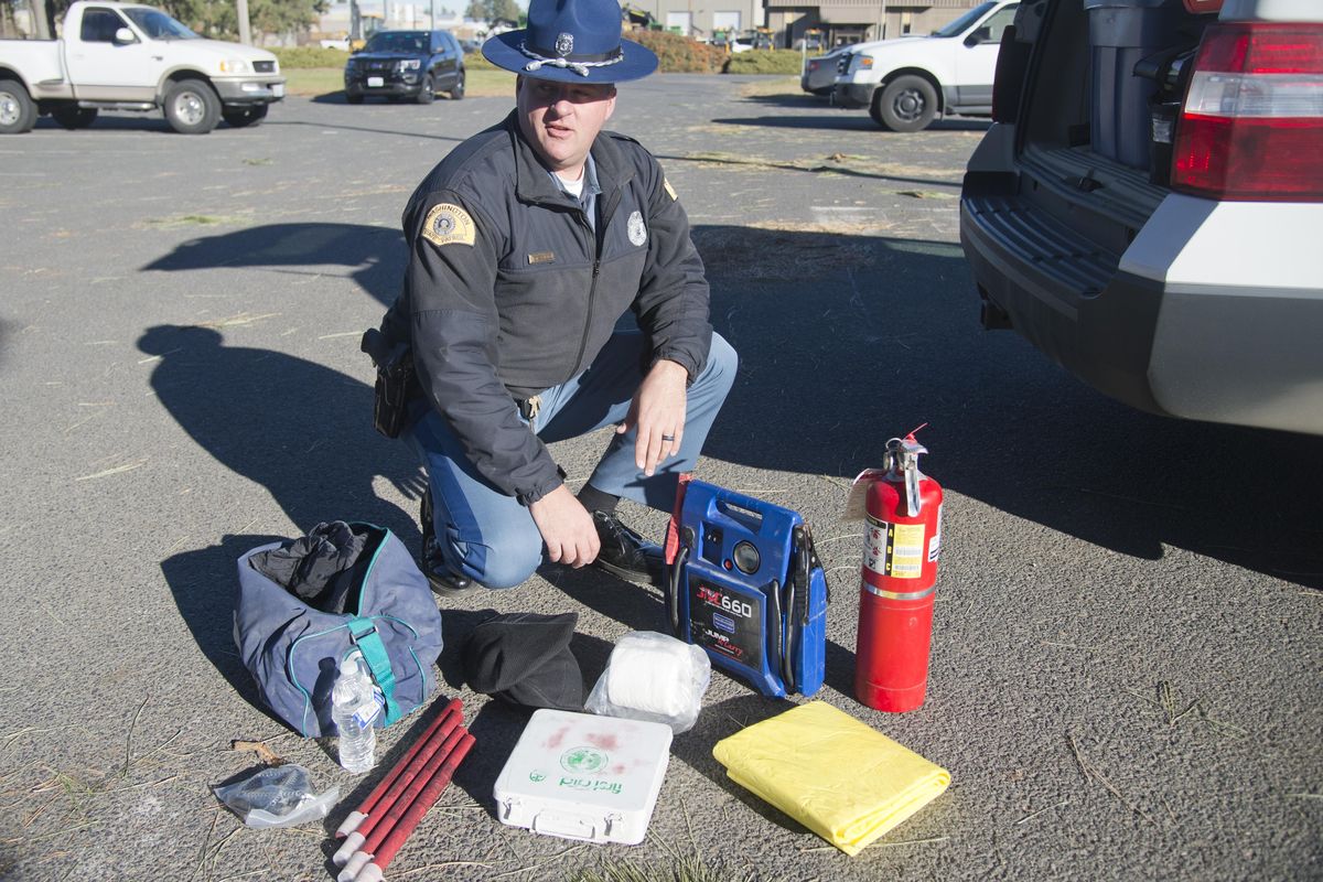 FILE – Trooper Jeff Sevigney of the Washington State Patrol shows off some of the winter safety gear he carries in the back of his patrol car Friday, Nov. 20, 2105, at the WSP headquarters in Spokane. (Jesse Tinsley / The Spokesman-Review)