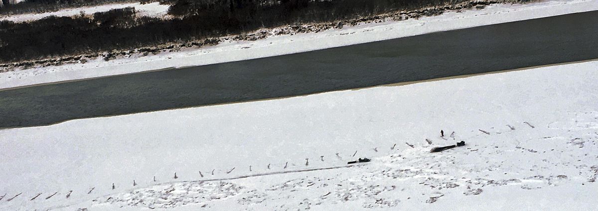 This January 2018 photo provided by Bethel Search and Rescue shows people and objects on a portion of the Kuskokwim River near Bethel, Alaska, that is partly covered by ice, not as much as usual this time of year. Months of higher-than-normal temperatures have opened dangerous holes in frozen rivers that rural Alaskans use as roads. (Associated Press)