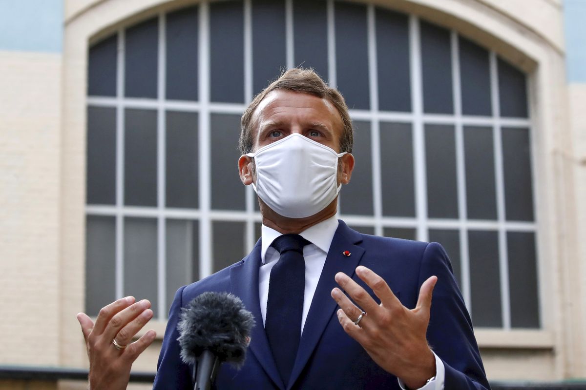 French President Emmanuel Macron, wearing a protective face mask, gestures as he speaks to the media as he visits a site of pharmaceutical group Seqens, in Villeneuve-la-Garenne, near Paris, Friday Aug. 28, 2020. French President Emmanuel Macron urged European neighbors Friday to better coordinate cross-border virus restrictions as infections resurge – and as multiple countries impose tests or quarantines on visitors from France. (Christian Hartmann)
