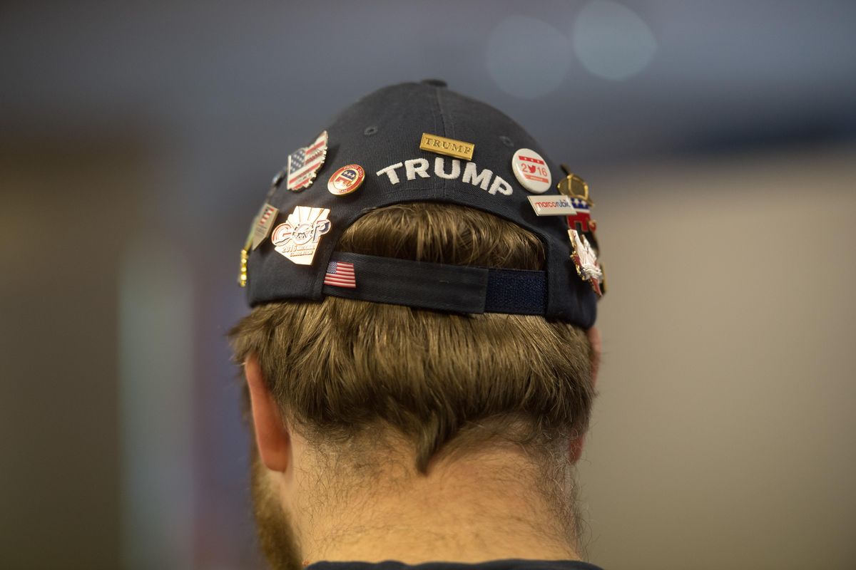 Kelly Lotze sports a collection of Trump pins he collected when serving as a GOP delegate in 2016 as he joins fellow Spokane area Republicans during a watch party for President-Elect Donald Trump