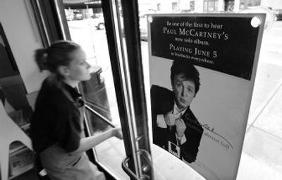 
A Starbucks barista   walks past a poster for  Paul McCartney's new  album, 