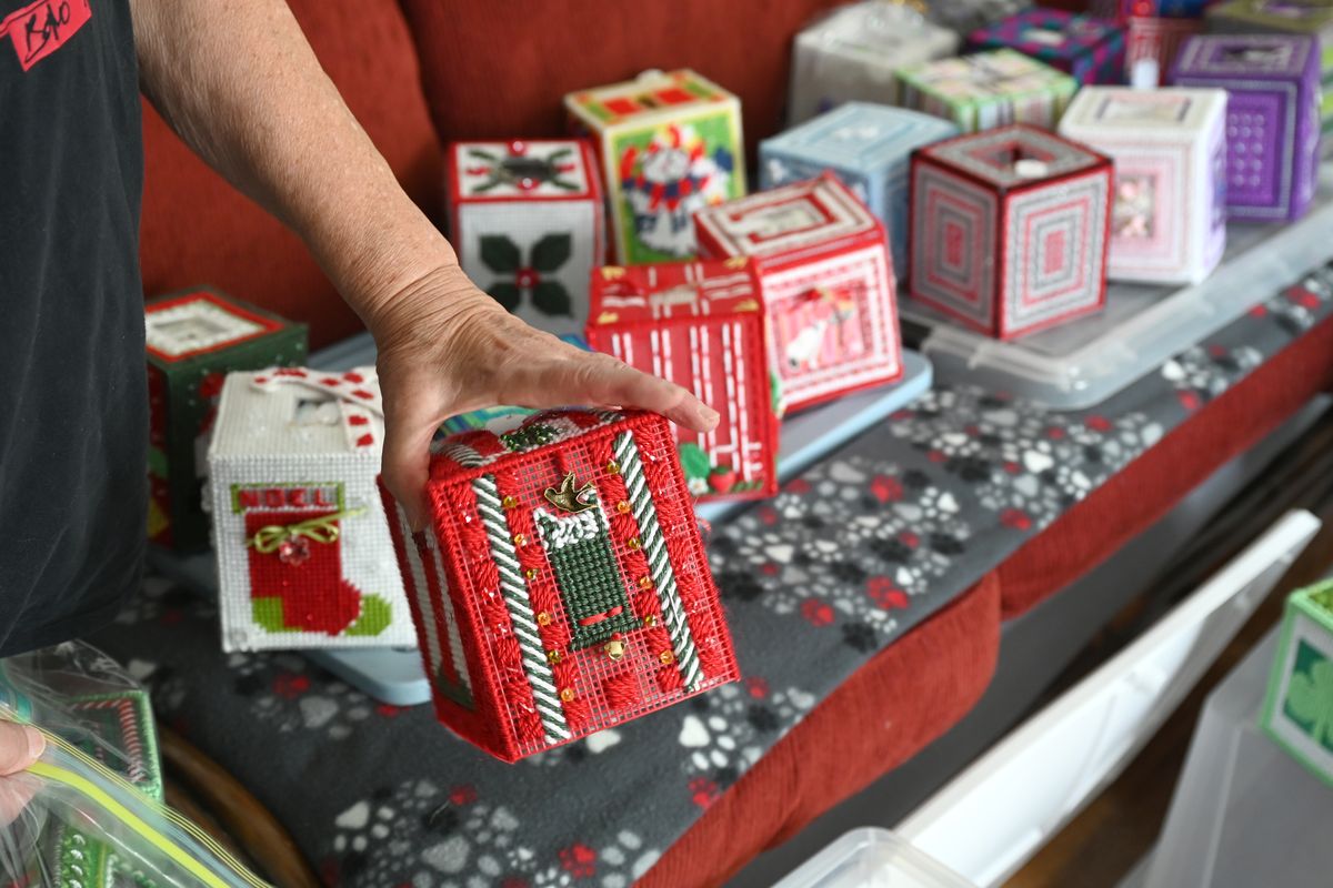 Darlene Kruse shows her Christmas-theme tissue box cover designs at her Shadle Park area home Aug. 10. She also has made other holiday-theme covers – St. Patrick
