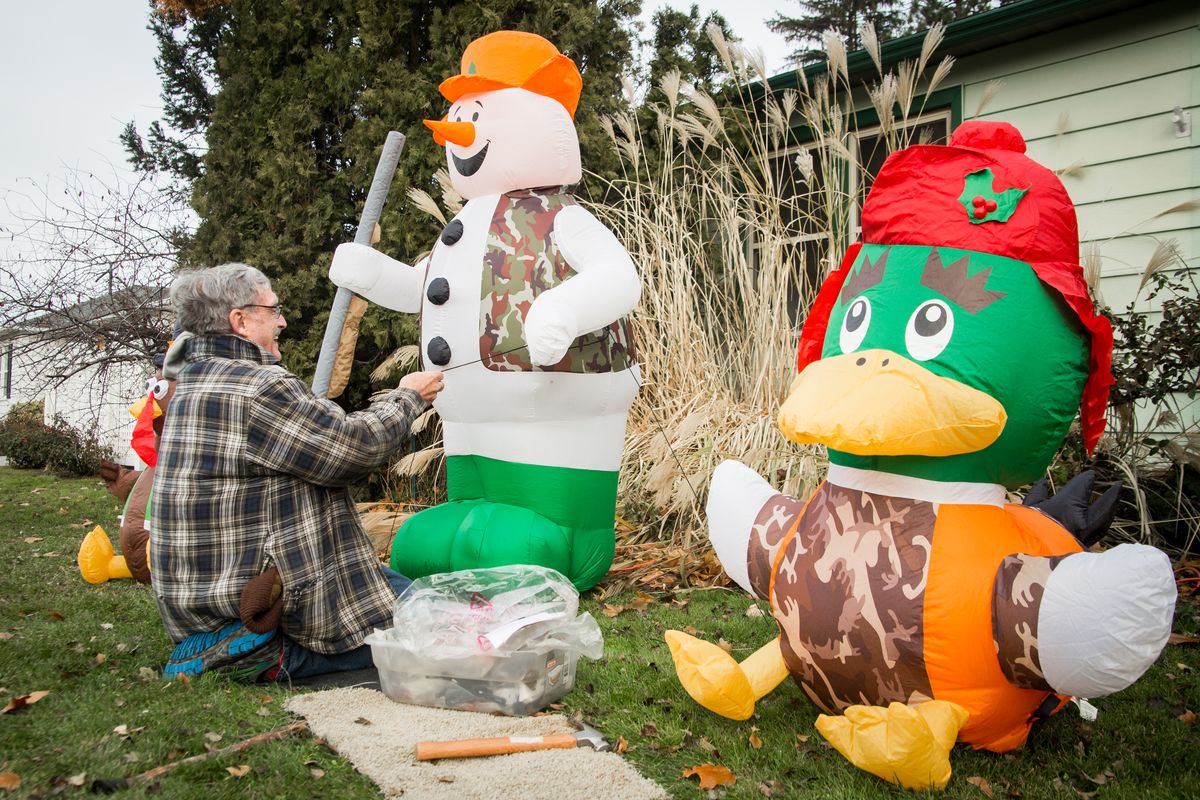 Bob George sets up three hunting-themed inflatables that double as Thanksgiving and Christmas decorations in his front lawn on Sunday, Nov. 22, 2020 in the South Hill neighborhood of Spokane, Wash. George said that he owns 63 holiday inflatables and that his grandchildren usually help him set them up all over the front and backyards, but this year’s coronavirus pandemic will prevent them from partaking in the decorating tradition.  (Libby Kamrowski/ THE SPOKESMAN-REVIEW)