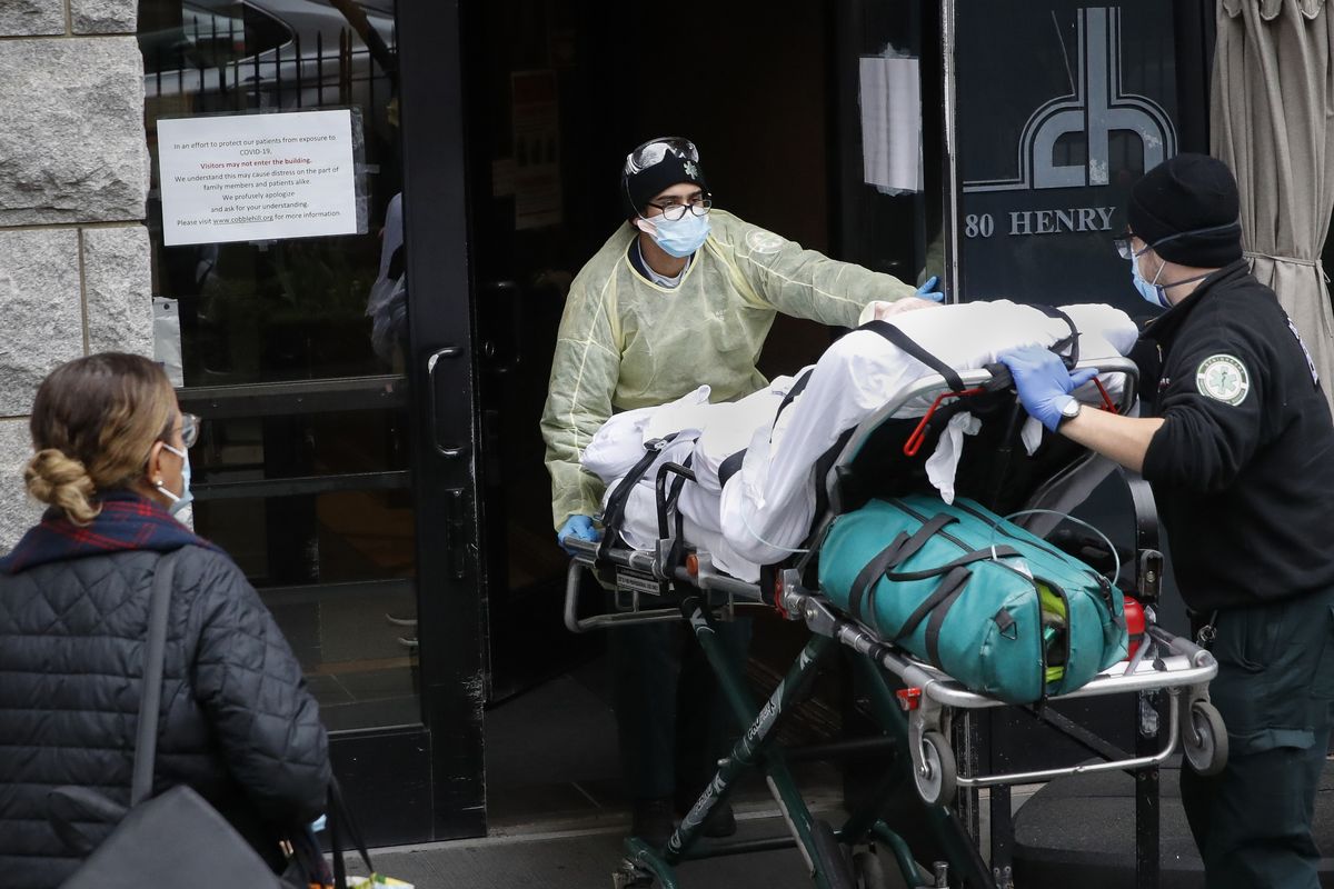 FILE- In this April 17, 2020, file photo, a patient is wheeled into Cobble Hill Health Center by emergency medical workers in the Brooklyn borough of New York. A grim blame game with partisan overtones is breaking out over COVID-19 deaths among nursing home residents, a tiny slice of the population that represents a shockingly high proportion of Americans who have perished in the pandemic.  (John Minchillo)