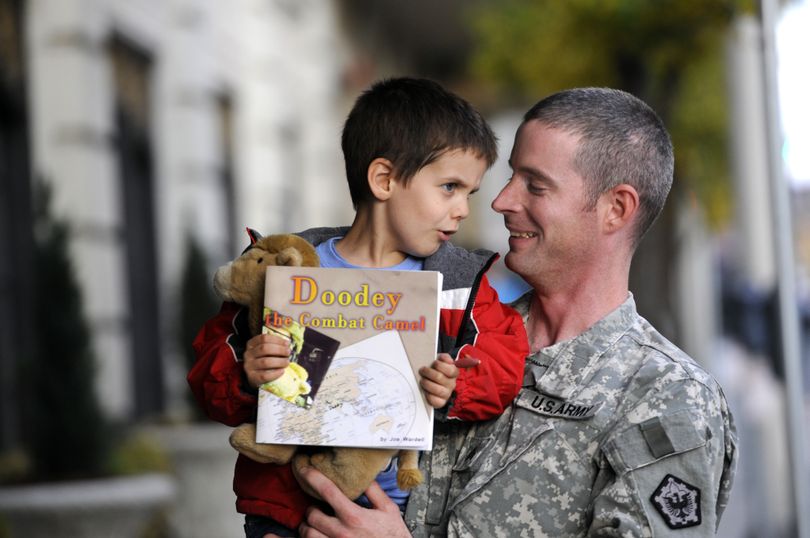 Joe Wardell holds his son, Clive, who holds the book Wardell wrote for him to explain to his son what he did in Afghanistan during his deployment. (Jesse Tinsley)