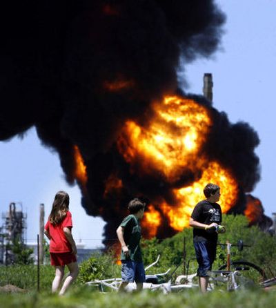 
Children play in a yard less than half a mile from a tank battery burning Saturday at an oil refinery in Wynnewood, Okla. 
 (Associated Press / The Spokesman-Review)