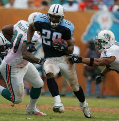 
Miami defender Jay Williams, left, and Junior Seau, right, take futile stabs as Tennessee running back Chris Brown breaks free for a 52-yard run in the second quarter. 
 (Associated Press / The Spokesman-Review)