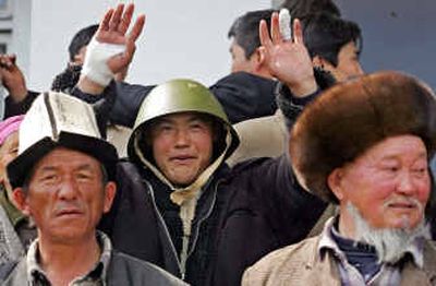 
A protester wearing a seized security forces helmet gestures while standing with other protesters wearing traditional Kyrgyz hats near an administration building that was captured by protesters Monday in Osh, Kyrgyzstan.
 (Associated Press / The Spokesman-Review)
