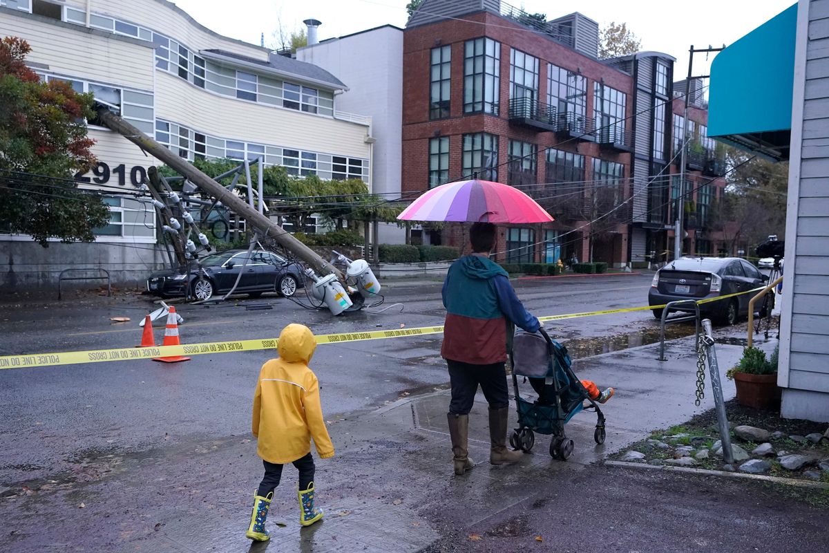 People walk past a downed power pole blocking East Madison Street in Seattle after it fell into an office building during a storm on Nov. 9, 2021.  (Ted S. Warren)